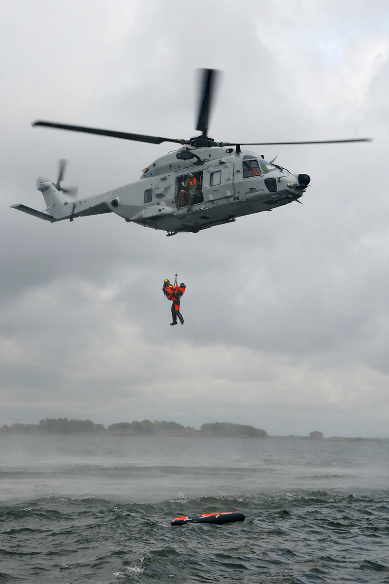 Helicopter rescue operation with a person being winched hanging below the helicopter
