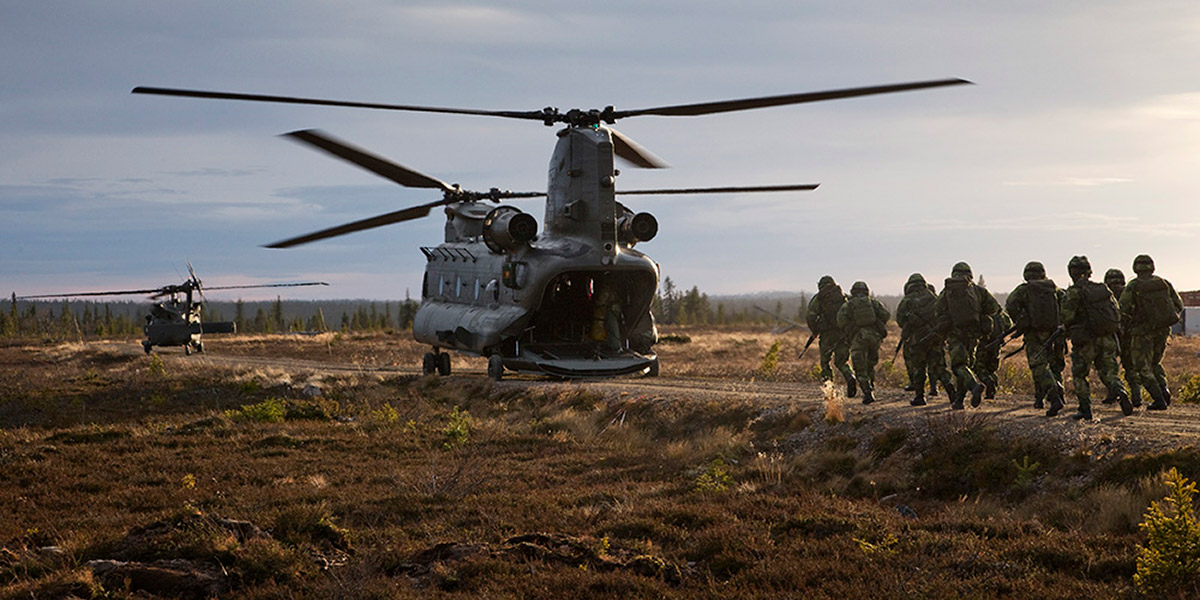 A group of soldiers moving towards a helicopter on the ground